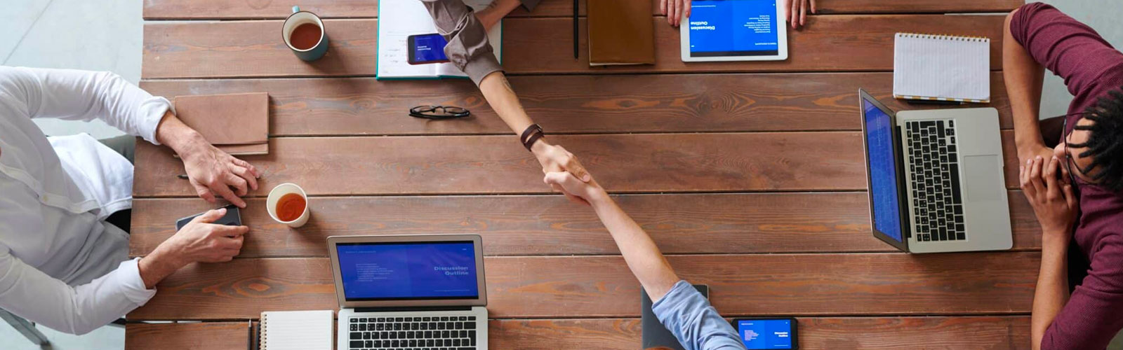 People shaking hands over table