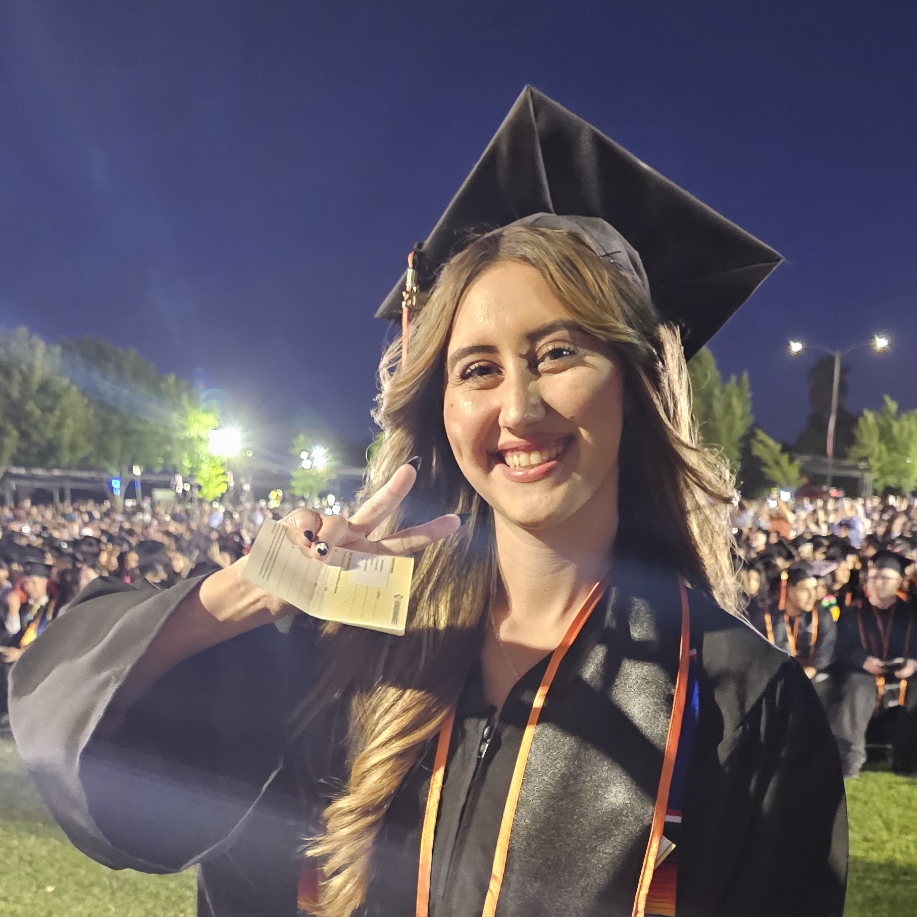 gradulating Reedley College student with peace sign in the air