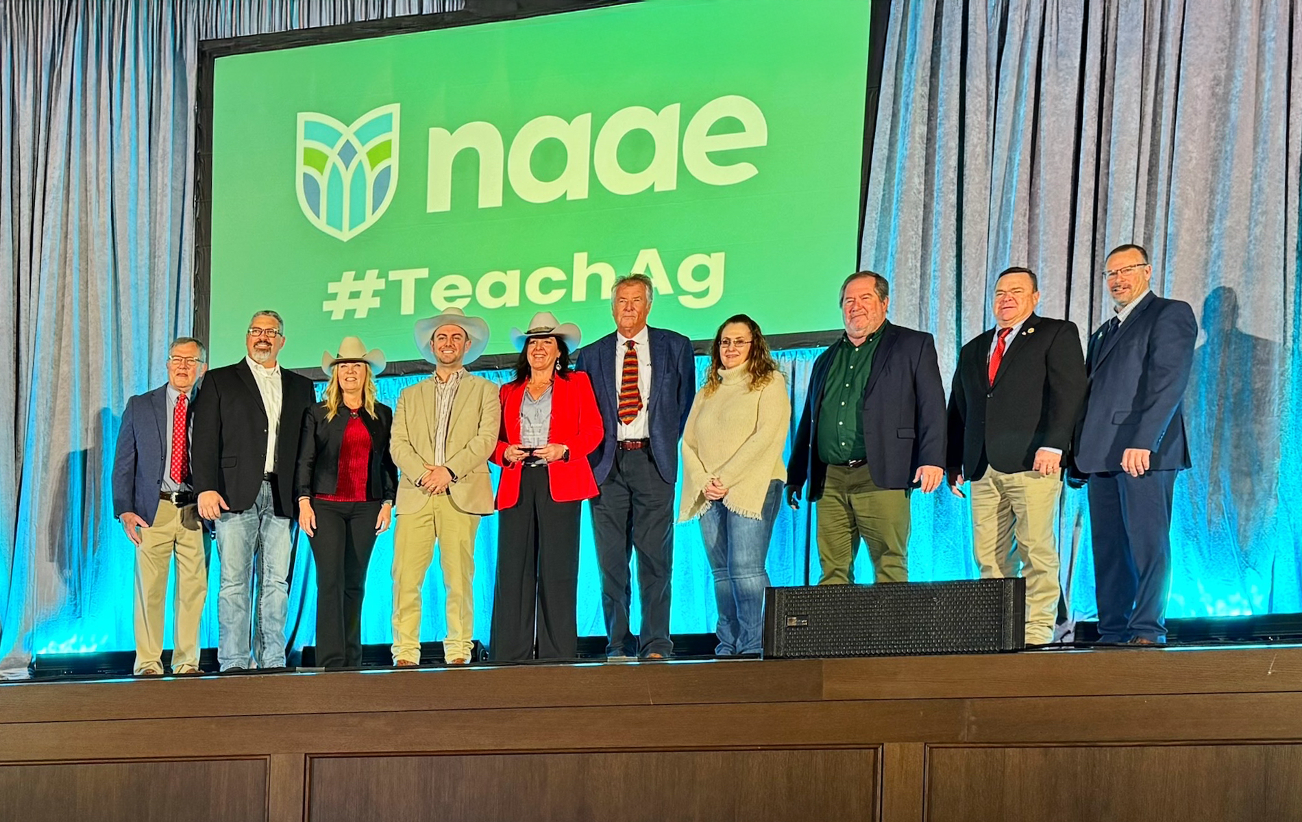 Group of educators and agricultural leaders standing on stage at a conference, showcasing support for agriculture education.
