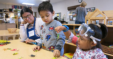 teacher and pre-k students in sandbox