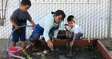 teacher and pre-k students in sandbox