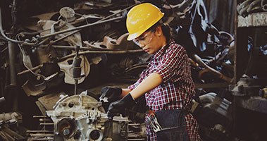 Woman with hard hat working on engine