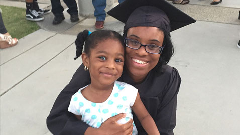 student graduating holding daughter